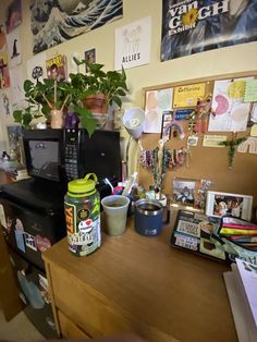 a cluttered room with various items on the desk and pictures hanging on the wall