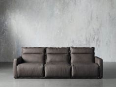 a couch sitting in front of a concrete wall with no one on it's legs