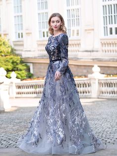 a woman in a blue and grey dress standing on a cobblestone walkway