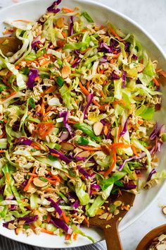 a white bowl filled with coleslaw slaw next to two wooden spoons