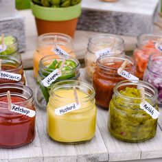 several jars filled with different colored food on a table next to a potted plant