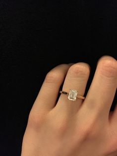 a woman's hand with a diamond ring on top of her finger, against a black background