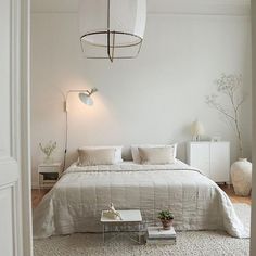 a bedroom with a bed, table and lamp in it