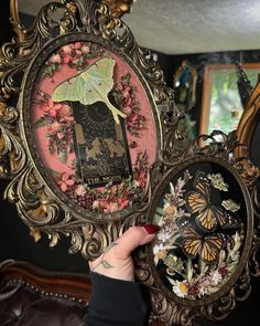 a person holding up an ornate frame with butterflies on it and the image of a woman's face