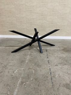 a black metal table sitting on top of a cement floor next to a white wall