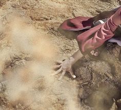 a person laying on the ground with their hands in the sand and one hand reaching for something