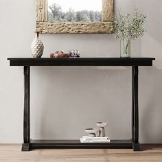 a console table with vases and flowers on it in front of a framed mirror