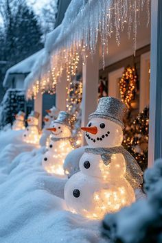 snowmen are lined up in front of a house with christmas lights