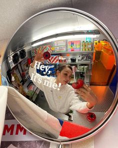 a woman holding an apple in front of a mirror