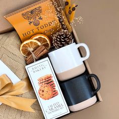 an open box with coffee, cookies and orange slices in it next to some cinnamons