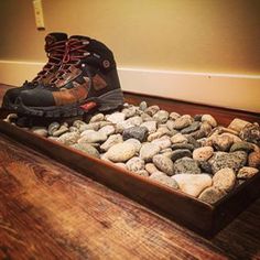 a pair of hiking boots sitting on top of rocks in a wooden tray filled with water