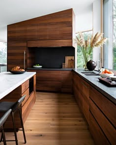 a modern kitchen with wood cabinets and black counter tops, along with an island in the middle