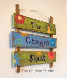 the chicken shack sign is made from wooden planks and has flowers painted on it