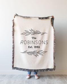 a woman holding up a white towel with the words, the robinsons est 1932 printed on it