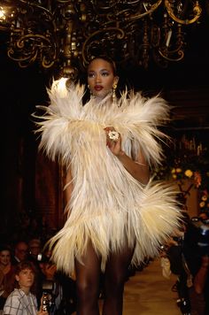 a model walks down the runway in a white feathered dress