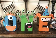 the letters are made out of wood and decorated with paper monsters, one is wearing a party hat