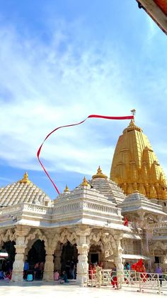 a white and gold building with red ribbon on it's roof in front of blue sky