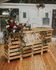 a bar made out of wooden pallets with flowers and greenery