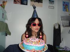 a woman wearing sunglasses blowing out candles on a birthday cake