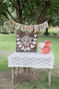 a wooden sign sitting on top of a table next to a basket filled with flowers