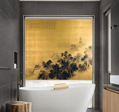 a bath tub sitting under a window next to a painting on the wall in a bathroom