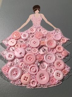 a woman in a pink dress made out of buttons on a piece of gray paper