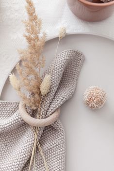 a white plate topped with a dried plant next to a napkin