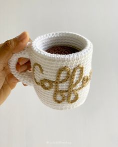 a hand holding a crocheted coffee cup