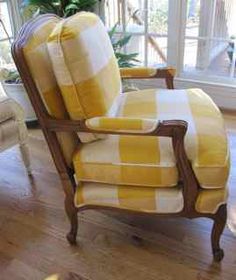 a yellow and white checkered chair sitting in front of a window with a potted plant