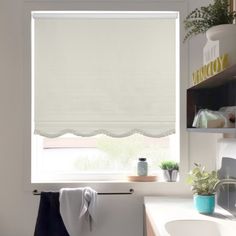 a bathroom with a sink and window covered in white roman blind shades over the windows