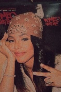 a woman with long hair wearing a bandana and holding her hand up to her face