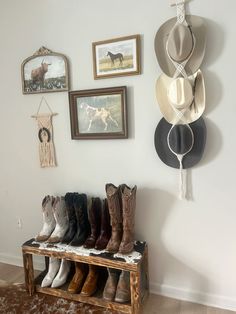 boots are lined up on a bench in front of pictures and other things hanging on the wall