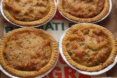 four small pies sitting on top of a pizza box covered in foil wrappers