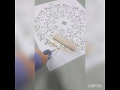 someone is using a pen to cut out a pattern on the paper with an adhesiver