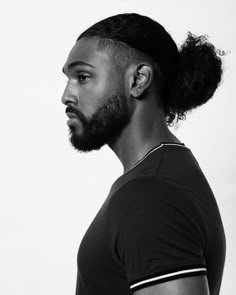 a man with a beard and a top knot in his hair looks off to the side