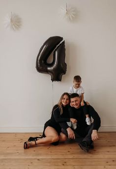 a man, woman and child are sitting on the floor in front of a balloon