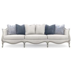 a white couch with blue pillows on the back and sides, in front of a white background