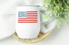 an american flag coffee mug sitting on top of a wicker basket next to a potted plant