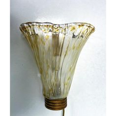 a glass vase is hanging on the wall next to a corded light fixture that has gold flecks in it