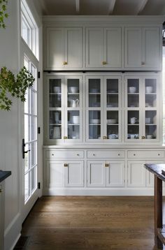 a kitchen with white cabinets and wood floors