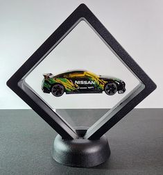 a toy car is in the center of a diamond shaped display stand on a table