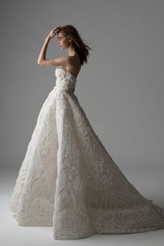 a woman in a wedding dress posing for the camera with her hand on her head