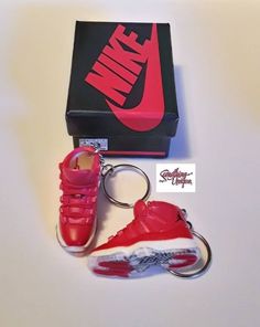 a pair of red nike sneakers are in front of a box and keychain