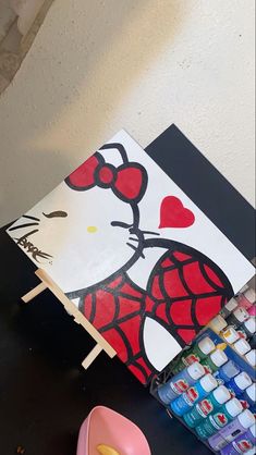 a table topped with art supplies and a hello kitty painting on top of each other