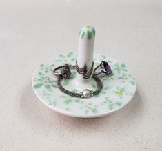 a white and green plate with a ring holder on it's side, sitting on a table