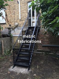 a set of black metal stairs next to a brick building with the words metallic fabrications written on it