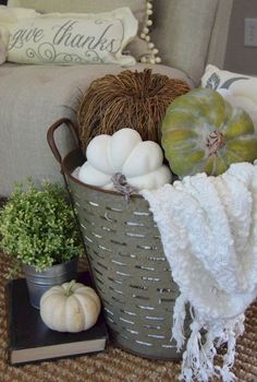 a basket filled with white pumpkins sitting on top of a rug next to a couch