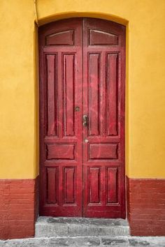 an open red door in front of a yellow wall