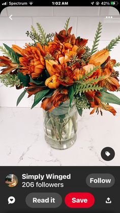 a vase filled with orange flowers sitting on top of a counter next to a phone