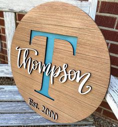 a wooden sign that says, thomas est 2000 on the side of a bench in front of a brick wall